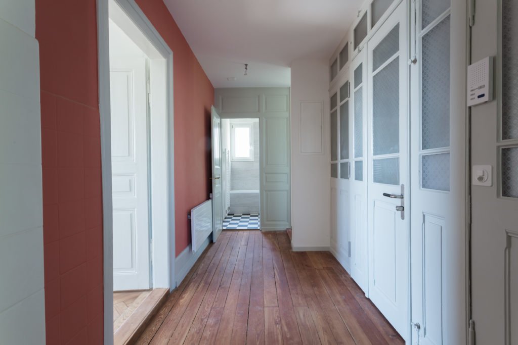 Korridor mit roter Akzentwand und hellen Türen