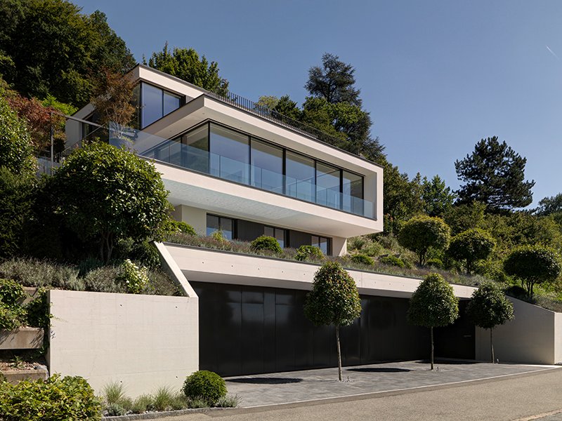 Seitliche Ansicht eines Hanghauses mit heller Putzfassade