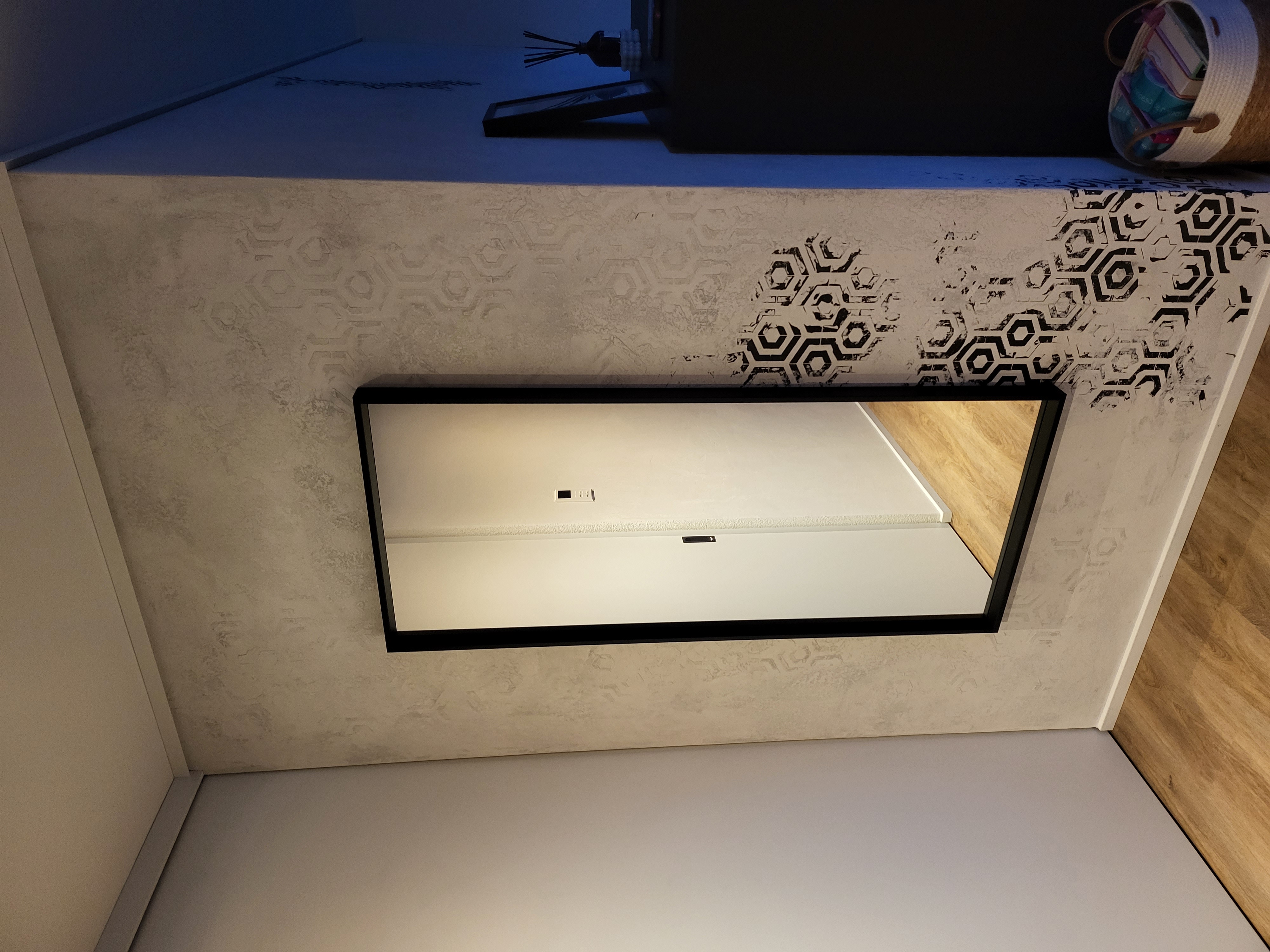 Gestaltete Wand im Eingangsbereich mit Spiegel und geometrischen Mustern