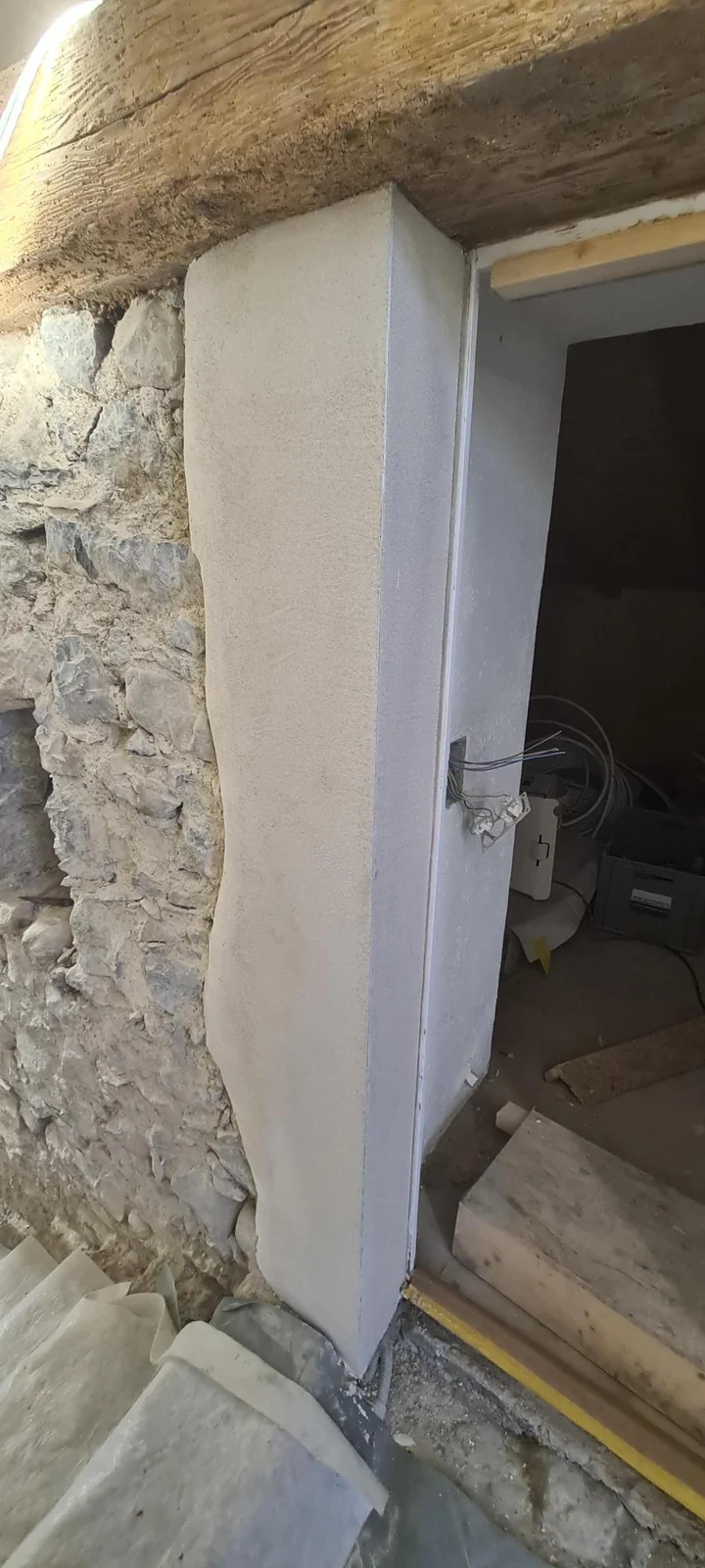 Verputzte TĂĽrleibung an einer freigelegten Natursteinwand