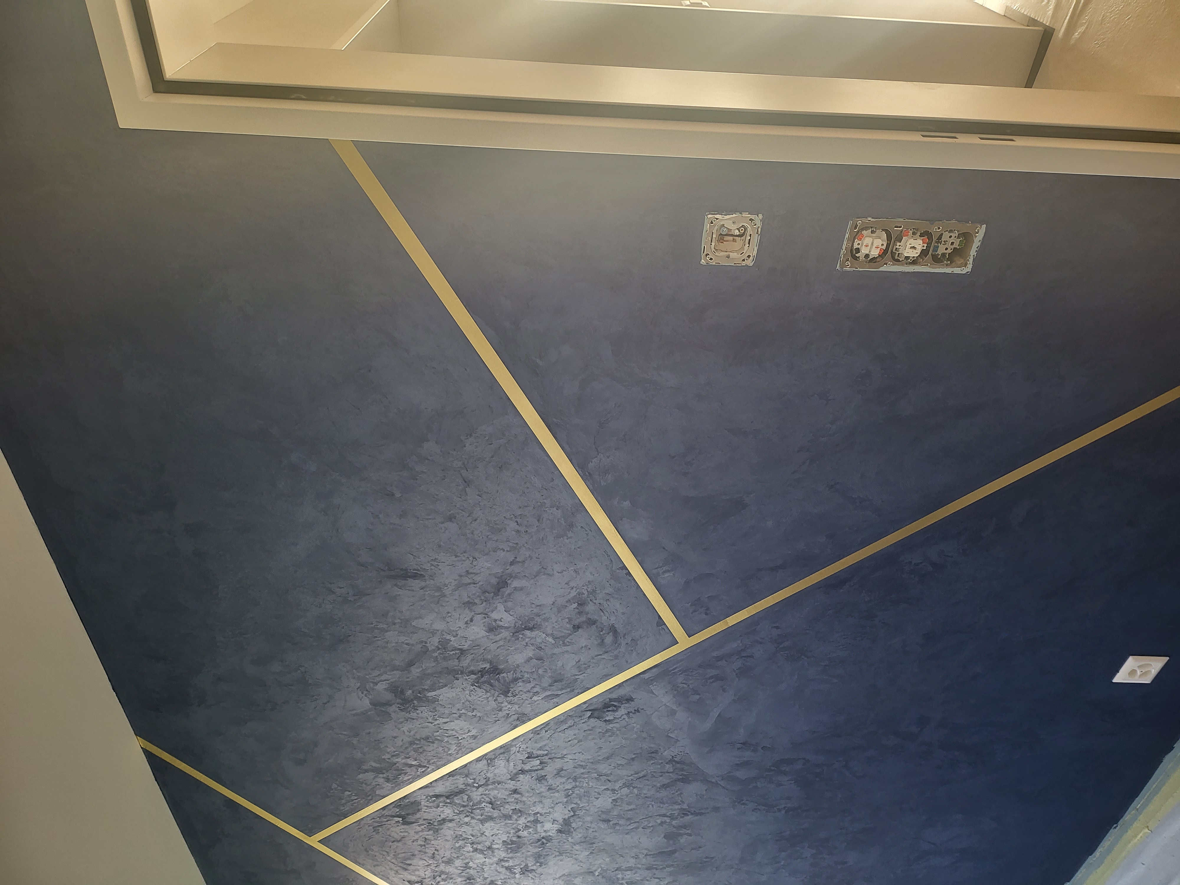 Blaue schimmernde Wandgestaltung mit goldfarbenen Linien