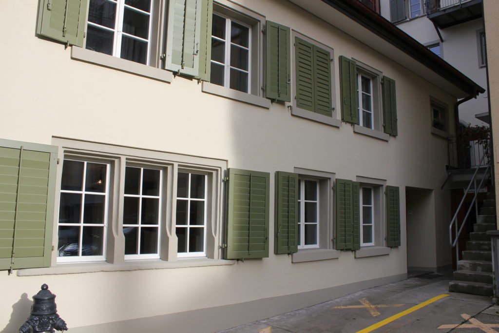 Fenster, Gewände und grüne Fensterläden an der sanierten Fassade