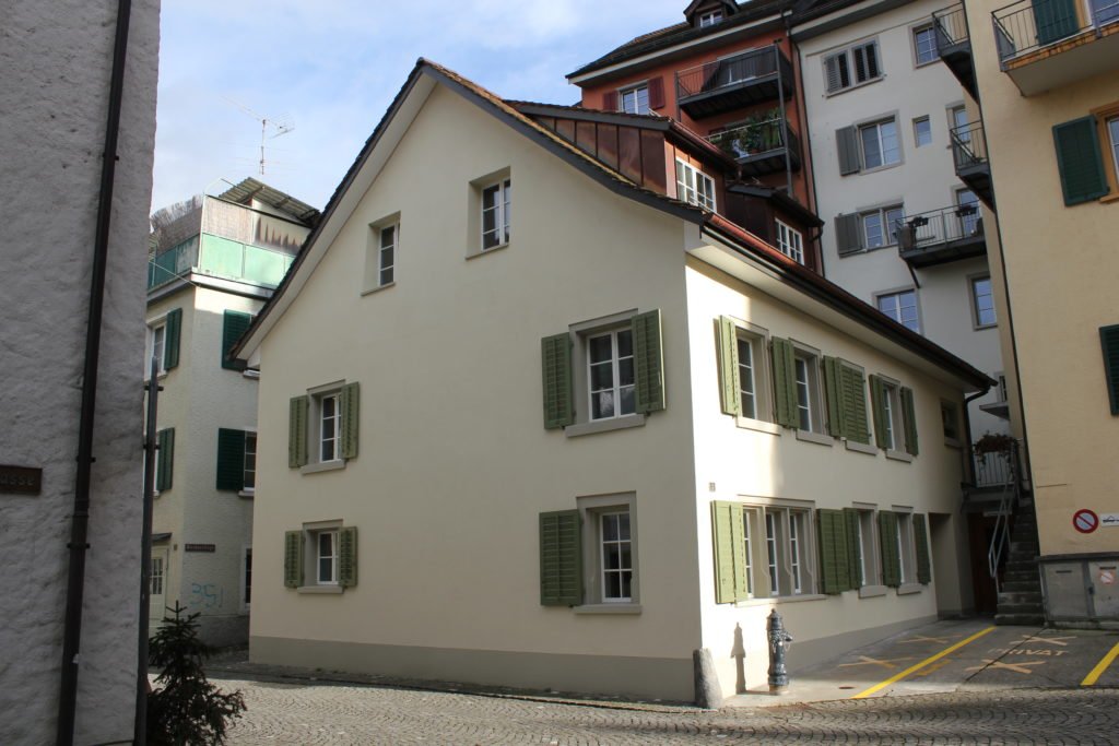 Historisches Gebäude mit heller Putzfassade und grünen Fensterläden in Bremgarten