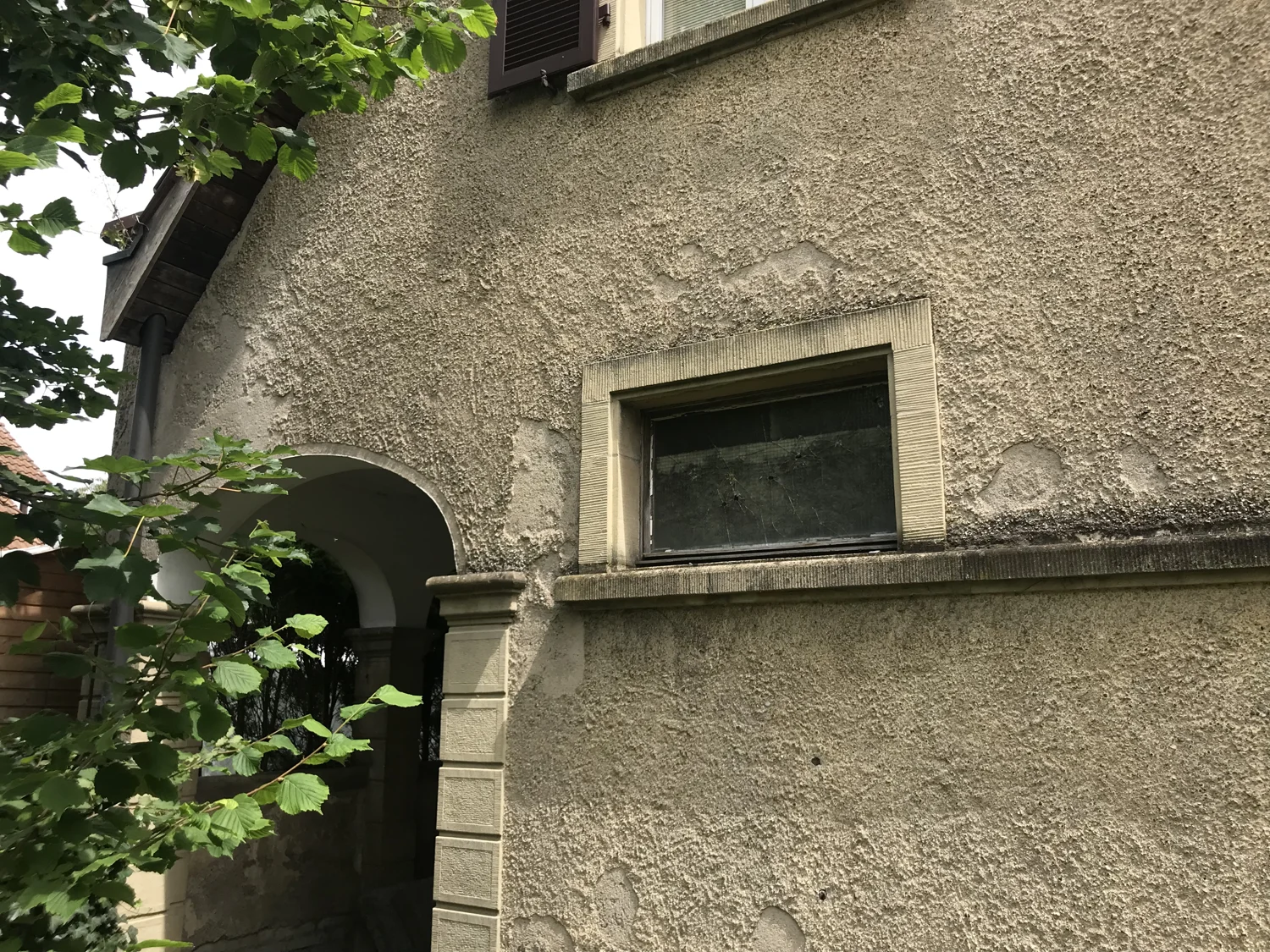 Ältere Fassade mit Kellenwurfputz und zahlreichen abgeplatzten Putzstellen