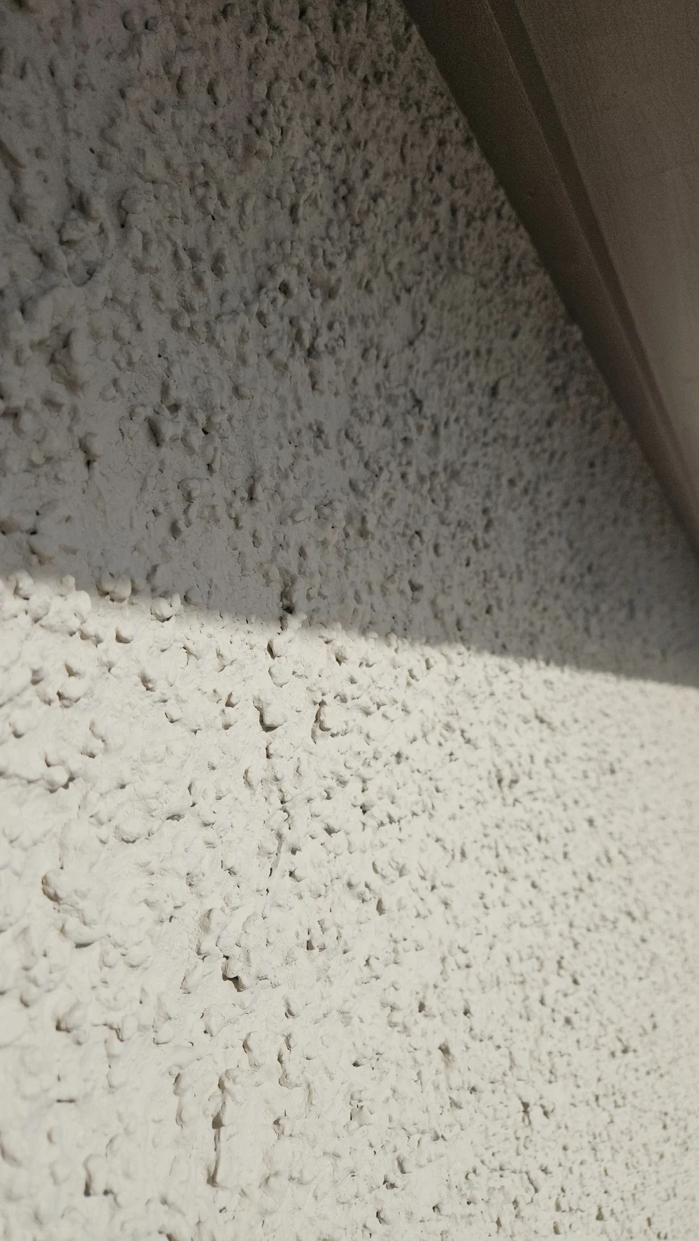 Nahaufnahme der groben Kellenwurfstruktur in Licht und Schatten