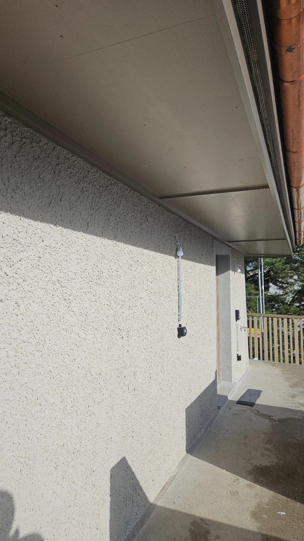 Ansicht einer hellen Fassade mit Kellenwurfputz entlang eines Balkons